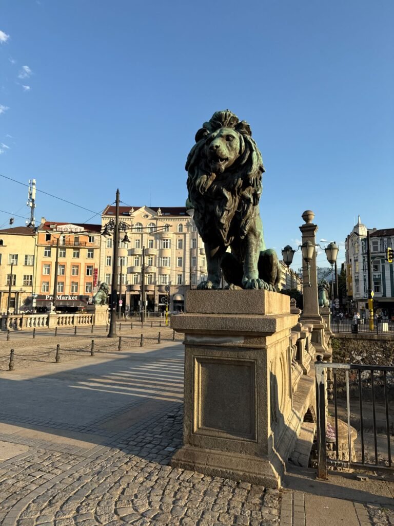 Bronze lion statue on Sofia's Lions' Bridge with the city skyline behind